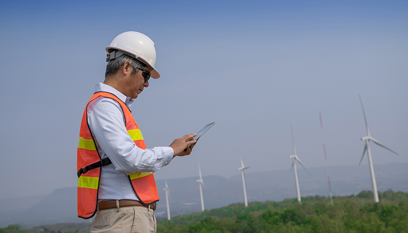 ABB employee looking at his mobile phone next to wind mills (photo)