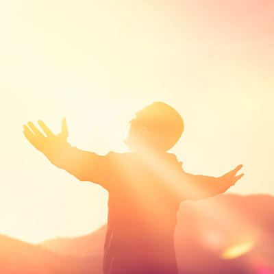 Man stretching arms and looking at the sun “looking positively towards the future” (photo)